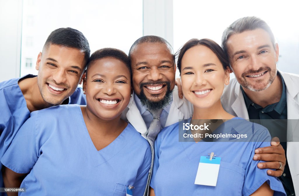 Shot of a cheerful group of doctors standing with their arms around each other inside of a hospital during the day Everyone plays their part here Nurse Stock Photo