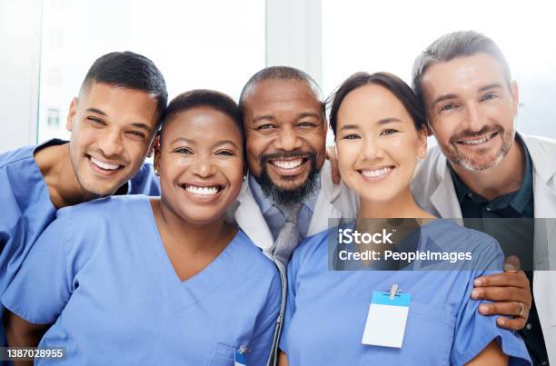 Shot Of A Cheerful Group Of Doctors Standing With Their Arms Around Each Other Inside Of A Hospital During The Day Stock Photo - Download Image Now