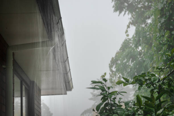 Roof gutter overflow in the heavy rain. Rain water cascading over the gutter.