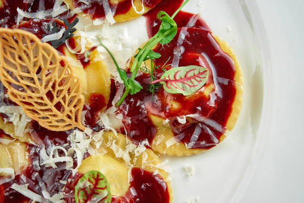 Ravioli with sauce and beef cheeks, Parmesan in a white plate on a white tablecloth. Close up, selective focus