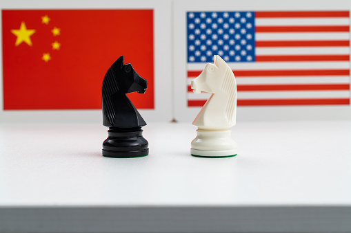 Two chess knights battle with American and Chinese flag.
