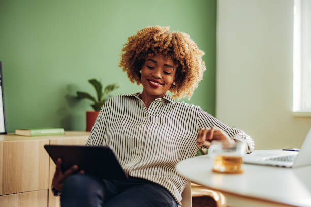 femme d’affaires heureuse utilisant une tablette numérique au bureau - desk on the phone sitting table photos et images de collection