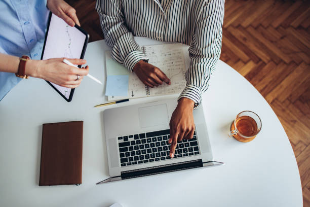 istock Two Unrecognizable Business Woman Working Together at Office Desk 1387035459