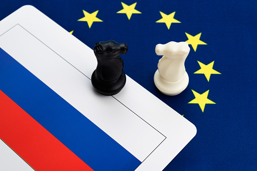 Two chess knights on European Union and Russian flag.
