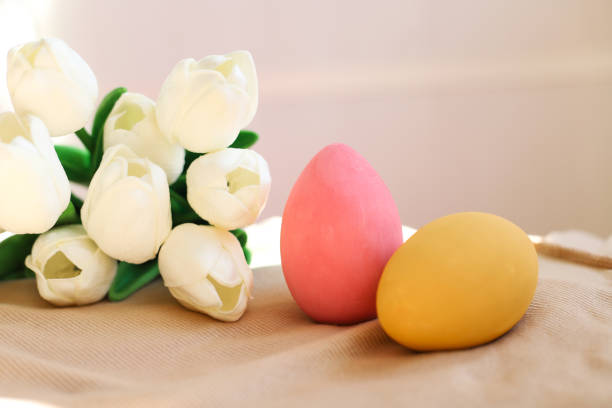 istock Two colored Easter eggs close-up and white tulips side by side. The concept of holidays and Easter 1387035576