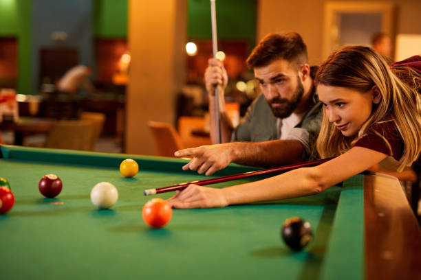Young happy couple enjoying playing billiard on a date in pool hall stock photo