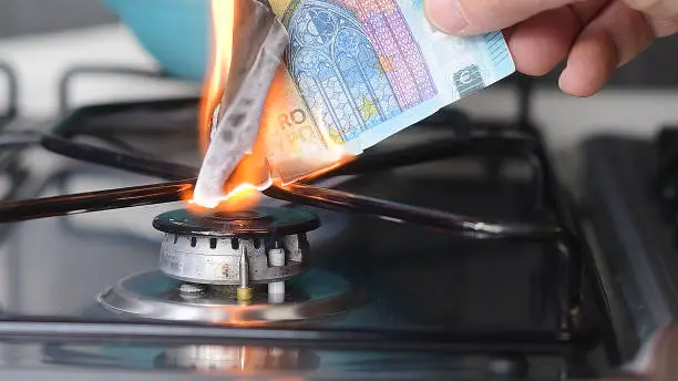 Photo of Gas price increase concept: 20 euro banknote burnt on a lit stove