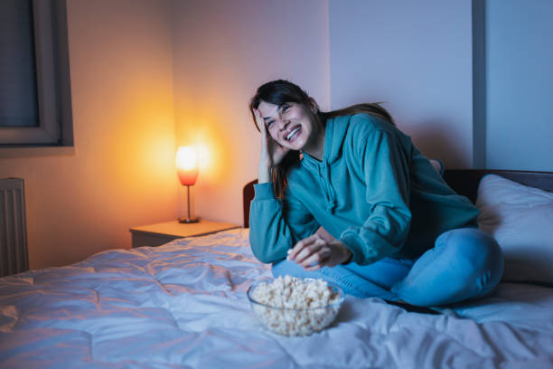 istock Woman eating popcorn while watching funny movie on TV 1387040521
