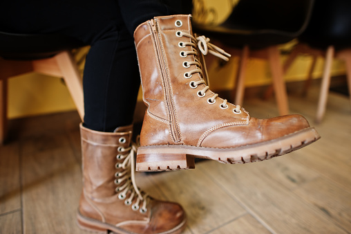 A girl wearing brown leather boots while sitting in cafe.