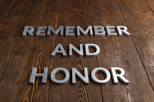 words remember and honor laid with silver metal letters on wooden background in linear perspective