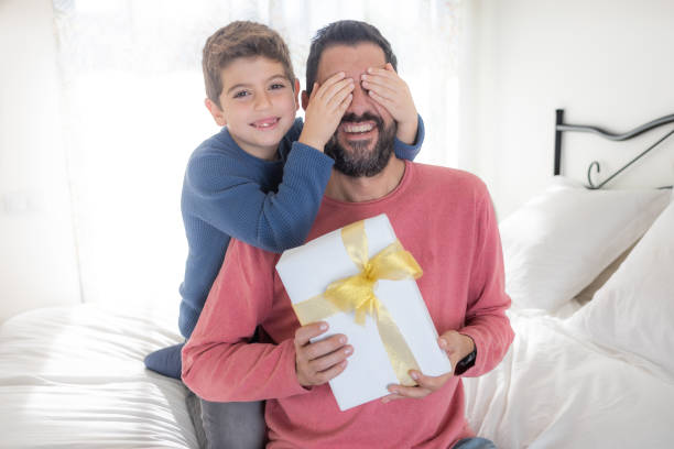 istock Son closing eyes to his father and giving a gift 1387042776