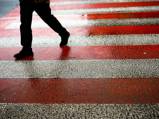 istock Male figure walking on red and white zebra crossing. 1387045928