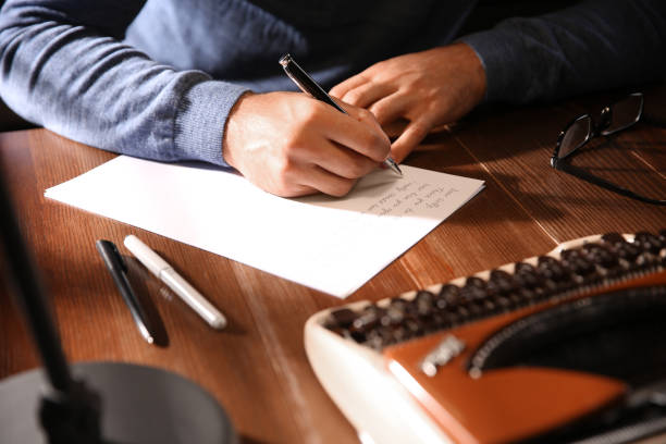 istock Man writing letter at wooden table indoors, closeup 1387046497