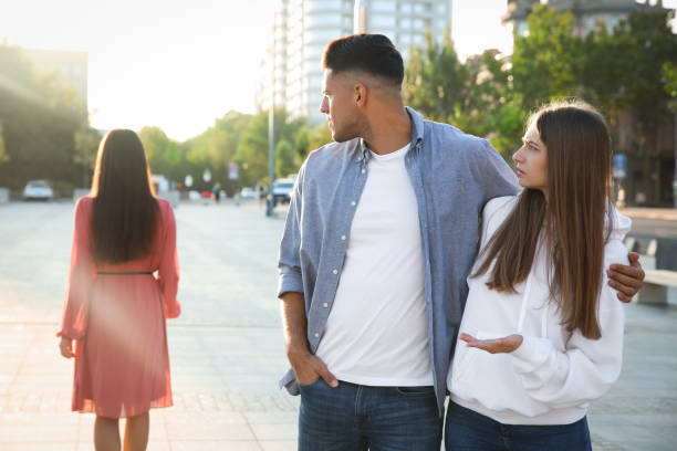 uomo sleale che guarda un'altra donna mentre cammina con la sua ragazza all'aperto - staring foto e immagini stock