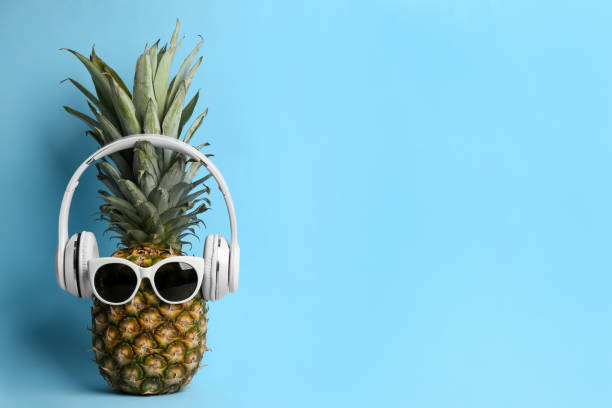 istock Pineapple with sunglasses and headphones on light blue background, space for text. Creative concept 1387046655