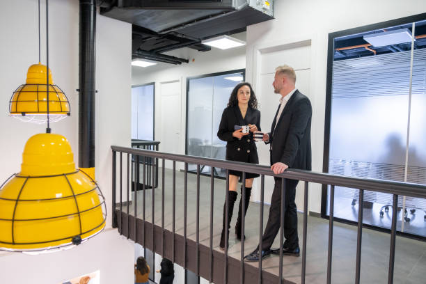 istock Two Colleagues Talking İn Office Corridor. 1387046723