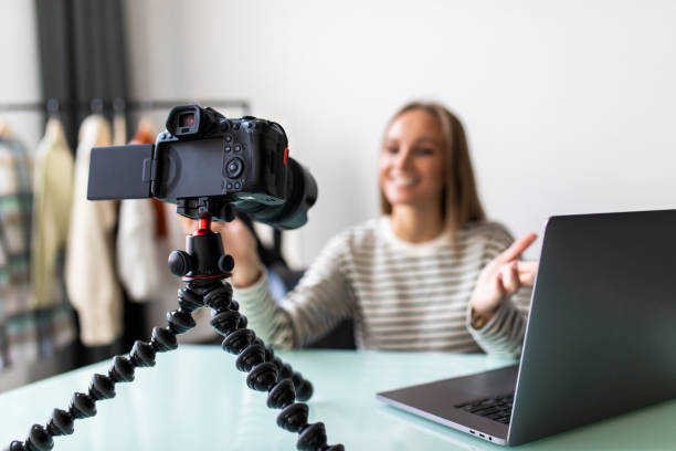 istock Female vlogger sitting beside desk with laptop, record herself 1387047367