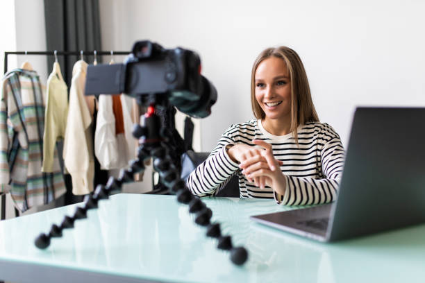 istock Confident young female vlogger sit at desk shooting live broadcast on professional camera. successful girl speaker or coach talk speak record video tutorial or blog at home 1387047644