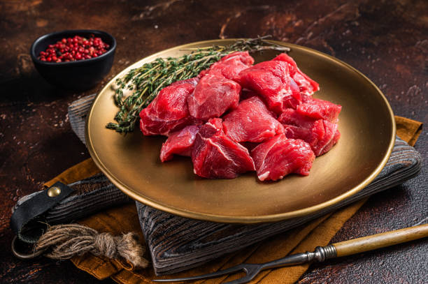 istock Raw diced lamb mutton meat with thyme. Dark background. Top view 1387048371