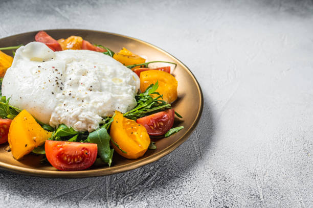 istock Italian Burrata cheese with cherry tomatoes and fresh arugula. White background. Top view. Copy space 1387048731