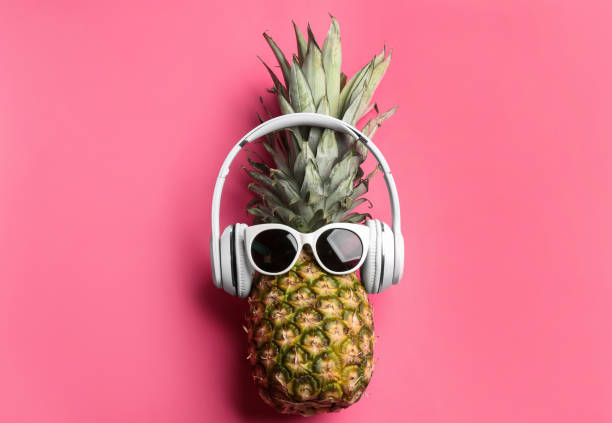 istock Pineapple with sunglasses and headphones on pink background, top view. Creative concept 1387048893