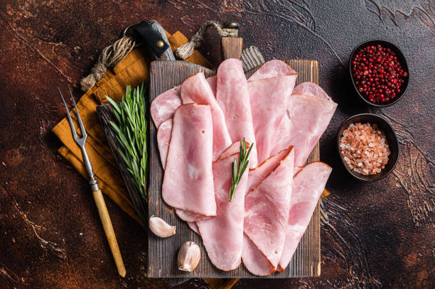 istock Flat slices of square sandwich ham with herbs. Dark background. Top view 1387049347