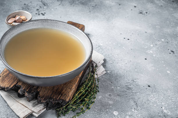 Bone meat chicken broth in a plate. Gray background. Top view. Copy space