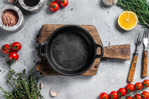 istock Various organic spices, herbs and ingredients around empty aged cooking skillet. Gray background. Top view. Copy space 1387050578