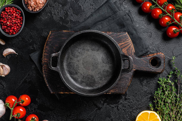 istock Various organic spices, herbs and ingredients around empty aged cooking skillet. Black background. Top view. Copy space 1387050610
