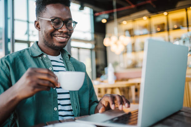 istock Young man sitting in coffee shop and using laptop. 1387051563