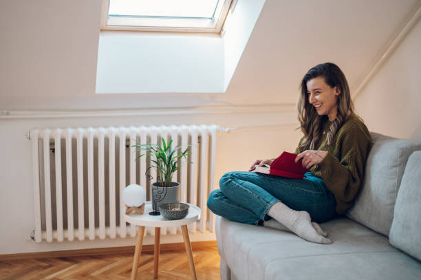 istock Woman reading a book while sitting on the couch at home 1387051689