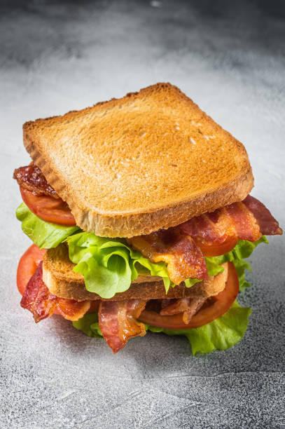 blt поджаренный сэндвич с беконом, помидорами и листьями салата. серый фон. вид сверху - sandwich delicatessen bacon lettuce and tomato mayonnaise стоковые фото и изображения