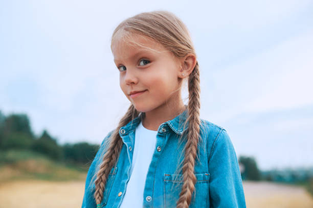 Close-up portrait of funny little girl with pigtails outdoor in summer day. Summertime stock photo