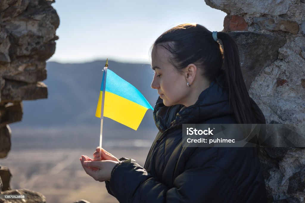 A young woman with the flag of Ukraine in her hands. A young sad woman with the flag of Ukraine in her hands, the concept of war in Ukraine. Ukraine Stock Photo