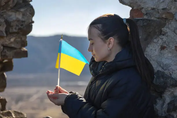 A young sad woman with the flag of Ukraine in her hands, the concept of war in Ukraine.