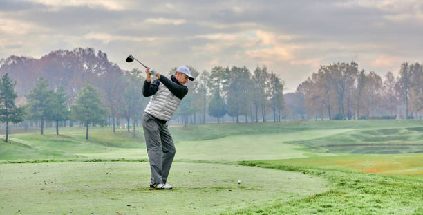 golfeur sur un terrain de golf en hiver avec brouillard et givre, sur le tee de départ. golfeur avec club de golf frappant la balle pour le coup parfait. le robinie golf club - sports flag golf individual sports sports and fitness photos et images de collection