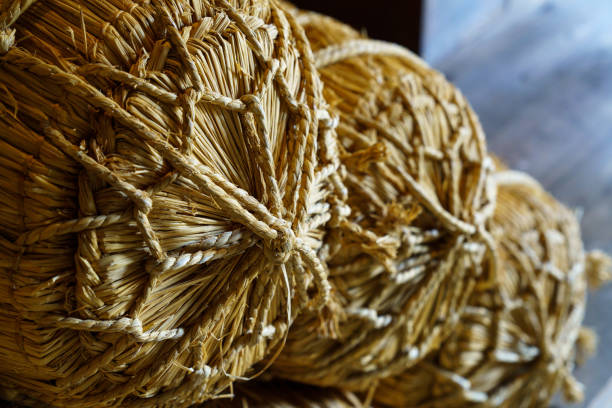 A close-up of the braided straw broom, with several thick and thin strips wrapped around it in red, blue, pink, and white colors.