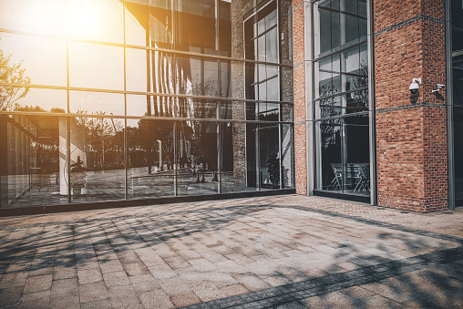 Stone pavement in front of brick and glass facades at the corner of city buildings in the evening