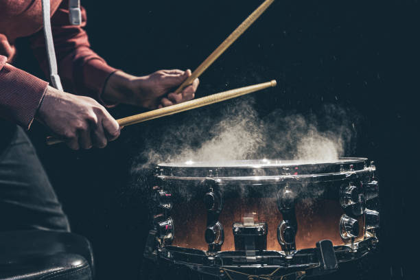 The drummer's hands hold drumsticks and play the snare drum. The percussionist plays with sticks on the floor tom on under studio lighting.. Concert and performance concept. drummer hands stock pictures, royalty-free photos & images