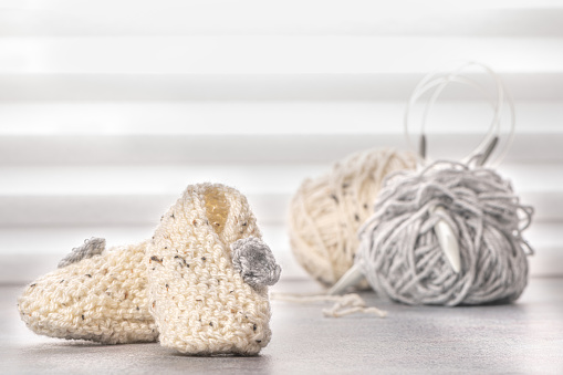 Knitting baby booties and wool yarns on soft background. Hand-made socks for the baby