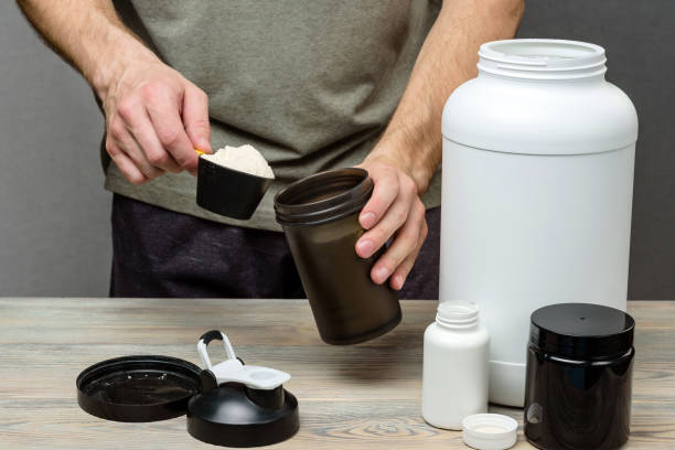 the athlete pours protein into a shaker. the concept of sports nutrition. - protein concentrate imagens e fotografias de stock