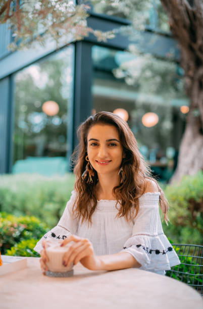 istock Young Woman is Drinking Coffee in Cafe 1387066929
