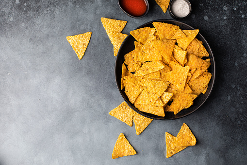 Corn Mexican tortilla chips snack on a black dark background.