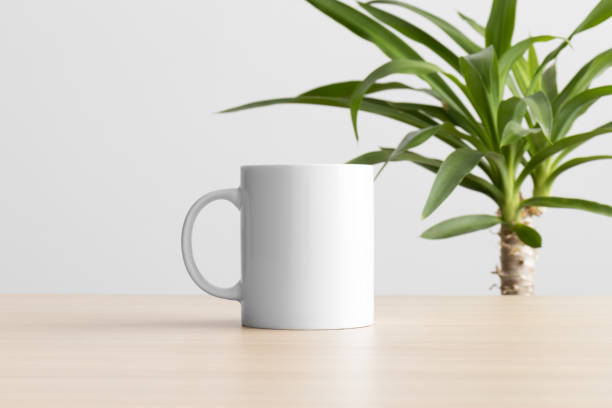istock White mug mockup on the wooden table with a yucca plant. 1387069310