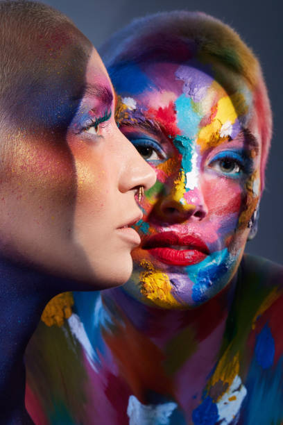 istock Studio shot of two young women posing with multi-coloured paint on her face 1387069360