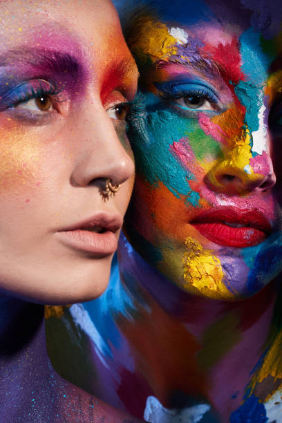 istock Studio shot of two young women posing with multi-coloured paint on her face 1387069713