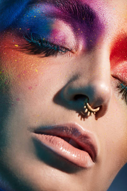 istock Studio shot of a young woman posing with multi-coloured paint on her face 1387069732