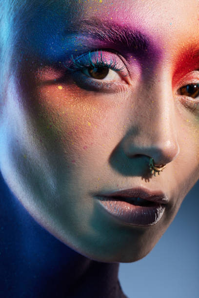 istock Studio shot of a young woman posing with multi-coloured paint on her face 1387069736