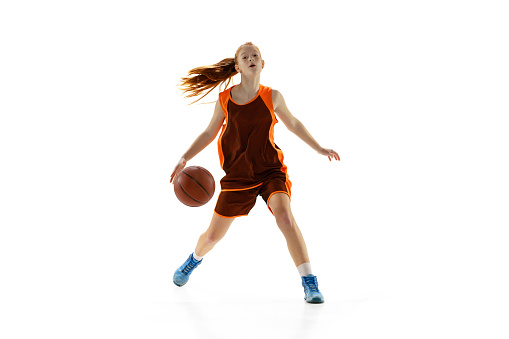 Ball possession. Portrait of young girl, teen, basketball player in motion, training isolated oer white studio background. Concept of professional sport, health, active lifestyle, hobby