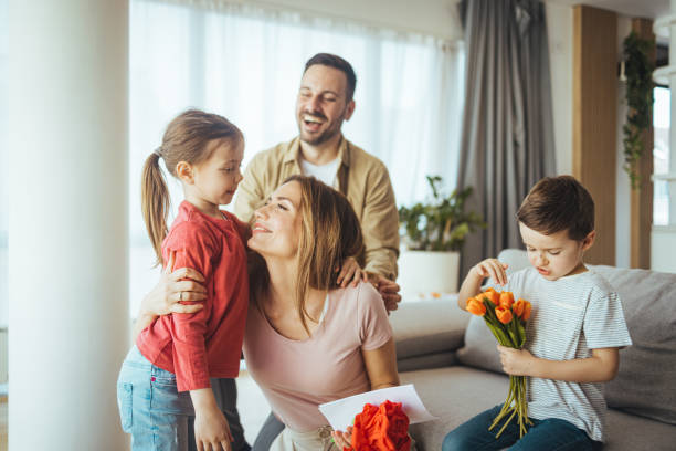 wesoła dziewczynka z kartką i najmłodszy brat z bukietem tulipanowych kwiatów - birthday present family facial expression birthday zdjęcia i obrazy z banku zdjęć